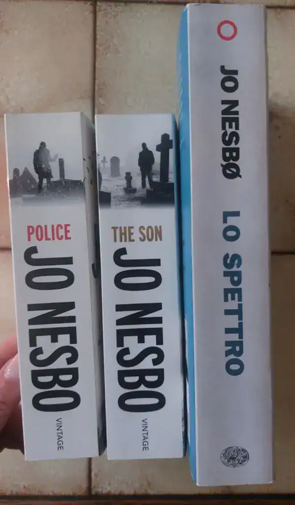 Tři knihy s názvy "Jo Nesbø" a "Police" a "The Son" na dřevěném povrchu.