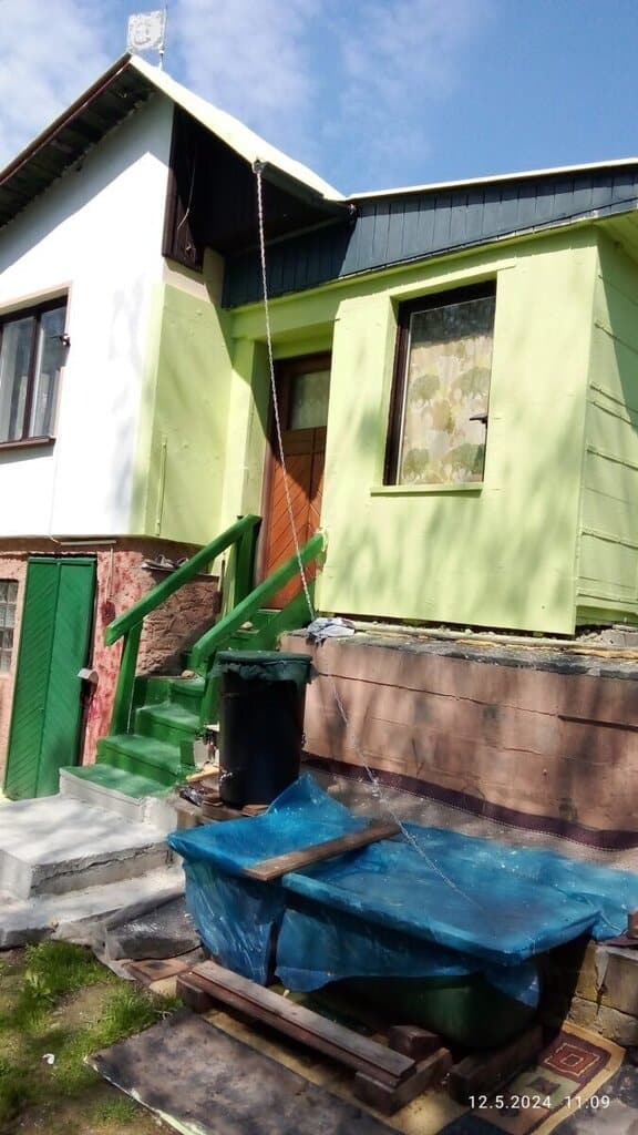 Částečně renovovaná fasáda a střecha rodinného domu s novým nátěrem.