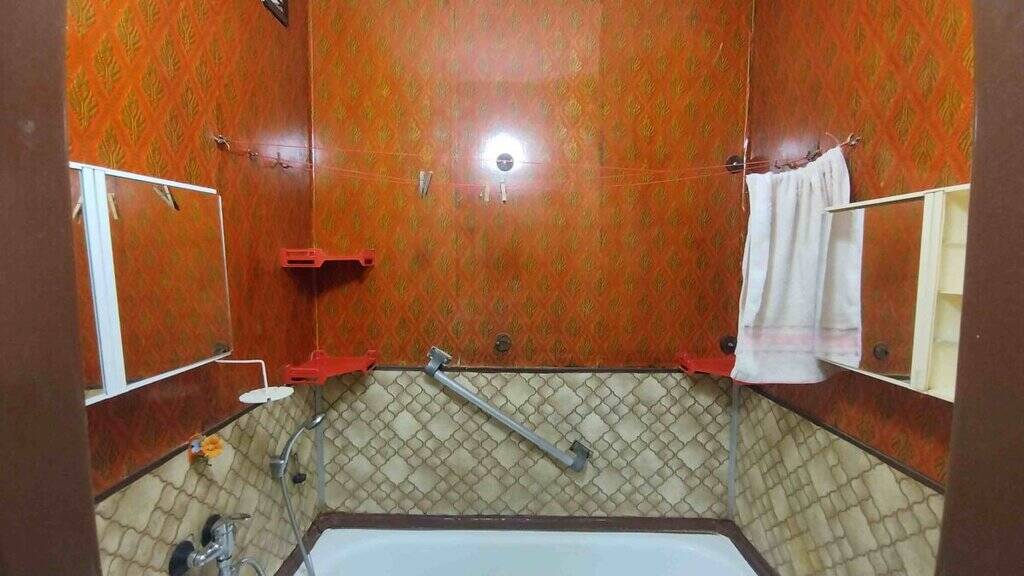 Staré koupelnové obklady a vana v malém bytě.