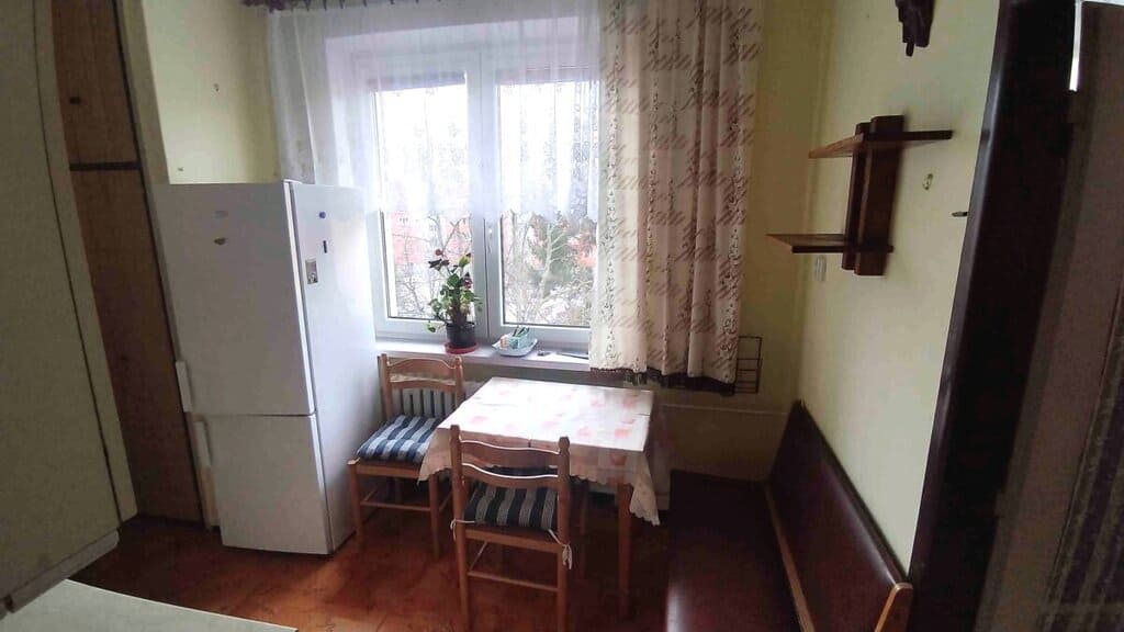 Interiér kuchyně s jídelním koutem a lednicí v bytě.