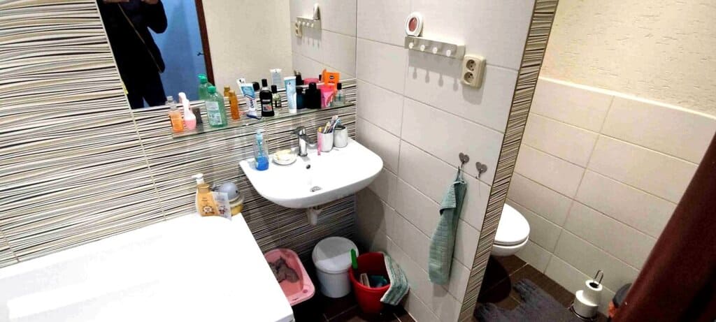 Umyvadlo s kosmetickými produkty na koupelnové skříňce.