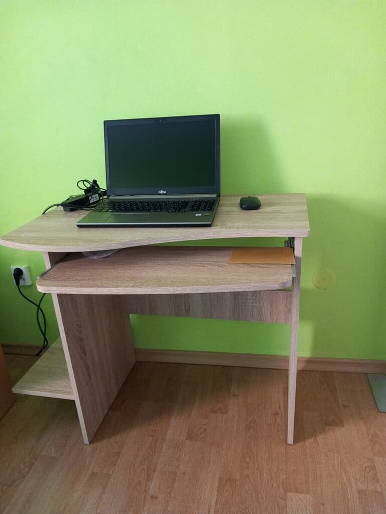 Počítač na psacím stole s monitorem, klávesnicí a myší v domácím prostředí.