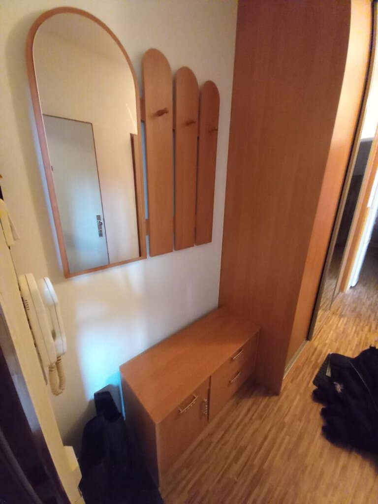 Věšák s několika zrcadly a botníkem v předsíni, ideální pro odložení kabátů a obuvi.