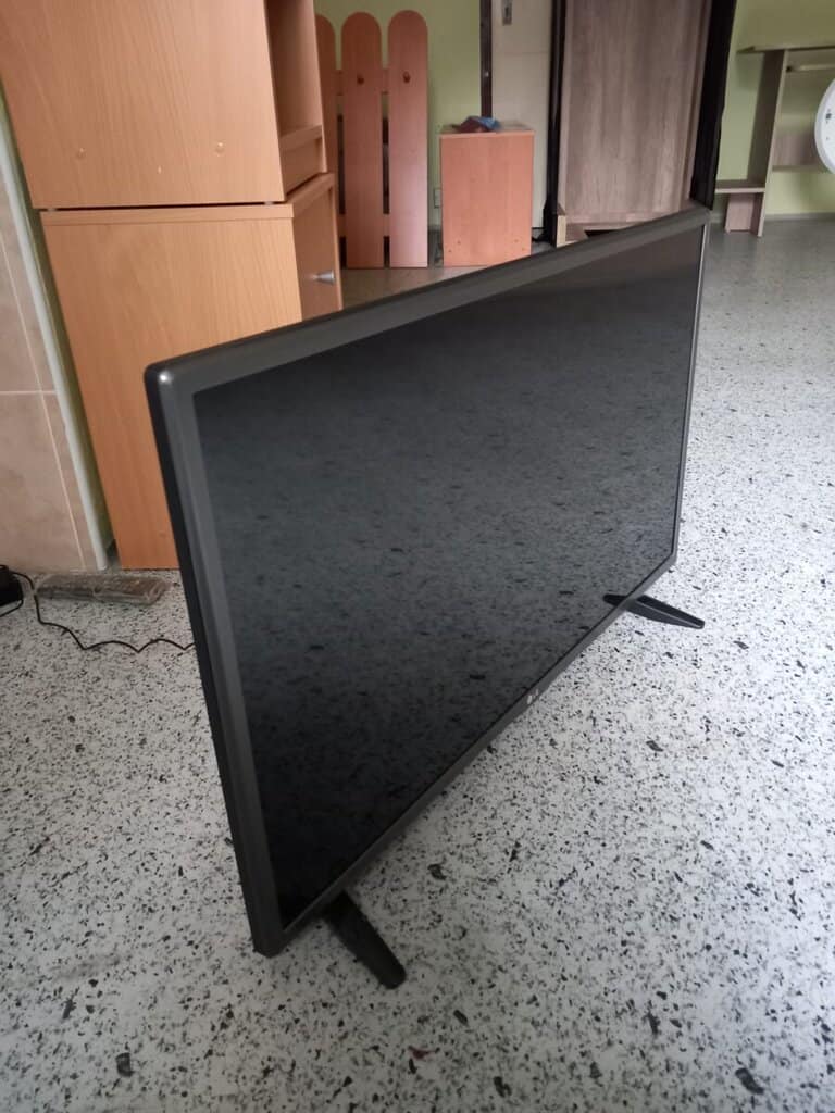 Moderní televizor s černým rámečkem na stojanu.