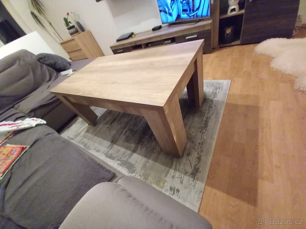 Dřevěný konferenční stolek v moderním obývacím pokoji s pohovkou a televizí.