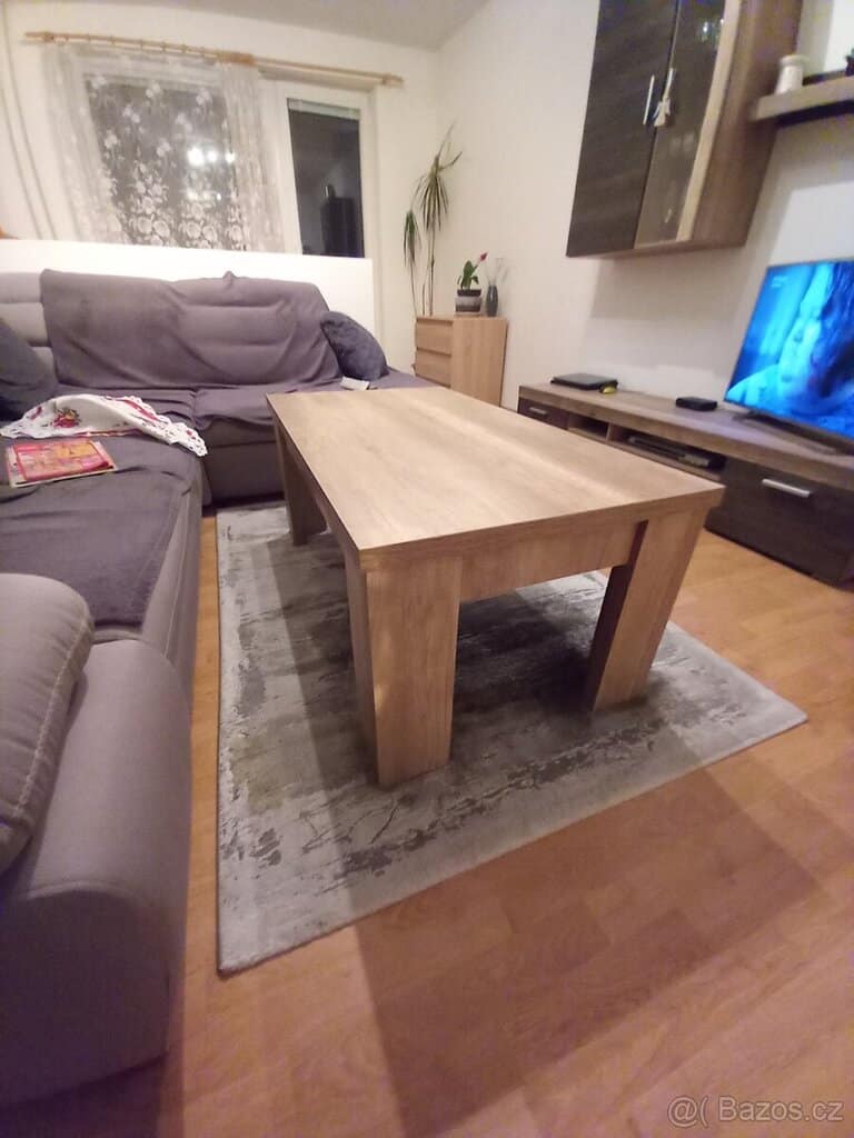 Dřevěný konferenční stolek v obývacím pokoji s pohovkami a televizí.