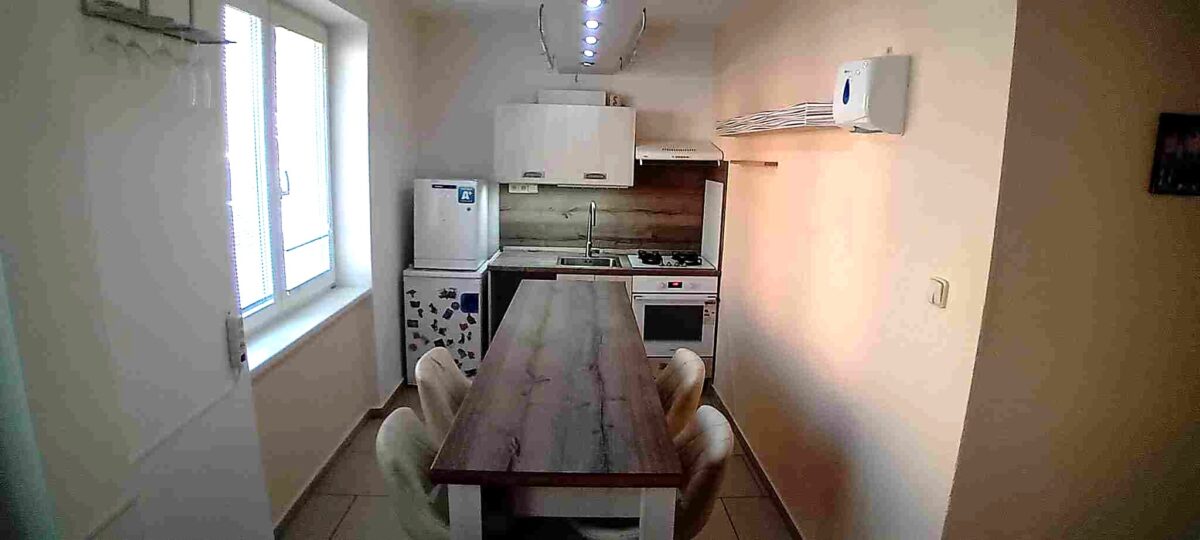 Kuchyně s jídelním stolem, sporákem a lednicí v moderním bytě.