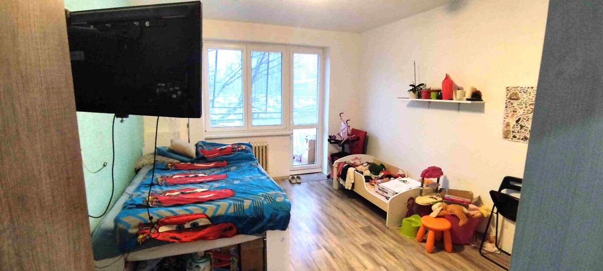 Dětský pokoj s dvěma postelemi, televizí a hracími prvky, ideální pro děti nebo studentské bydlení.