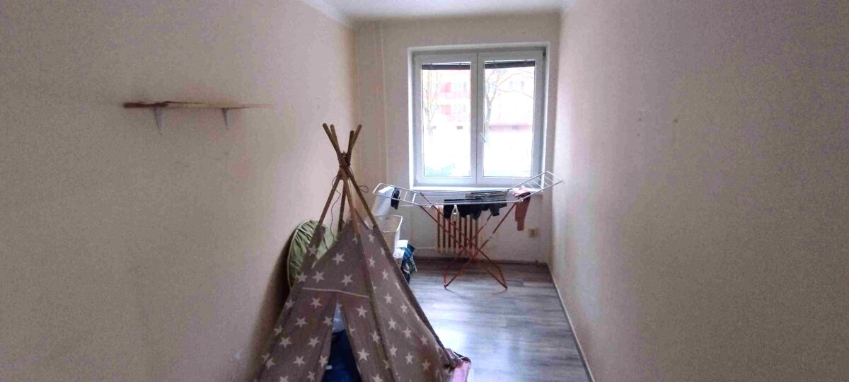 Prázdný dětský pokoj s oknem a stanem na hraní.