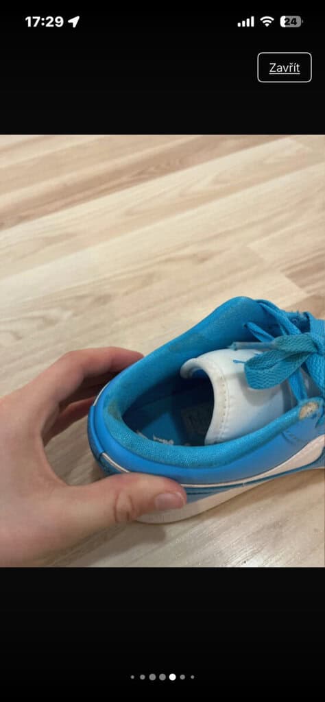 Dětské modré tenisky s tkaničkami na ploché podlaze.