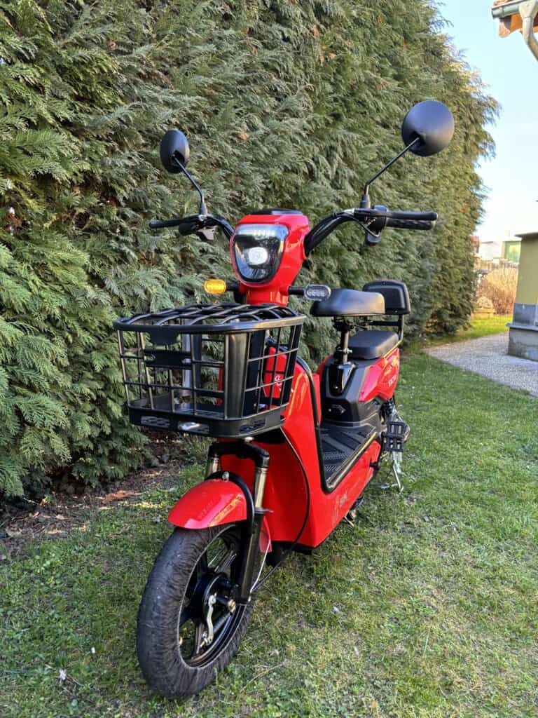 Elektrická koloběžka s černým košíkem na přední straně, ideální pro městské přesuny.