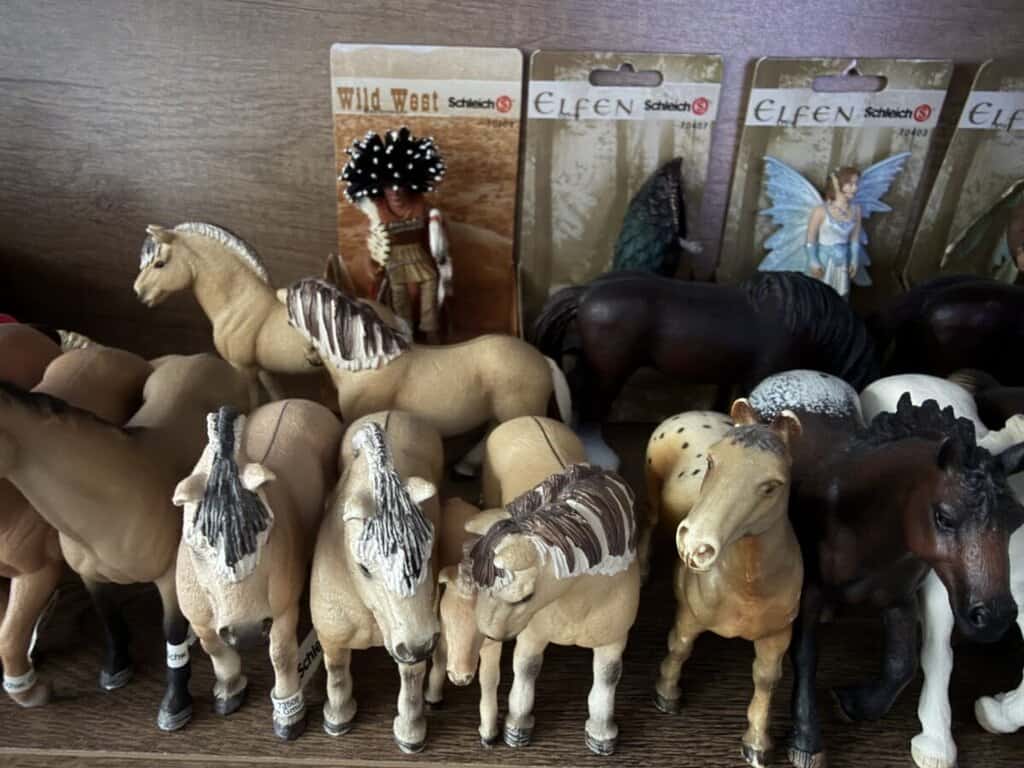 Figurky koní a pohádkové postavičky na prodej v bazaru, vhodné pro sběratele a děti.