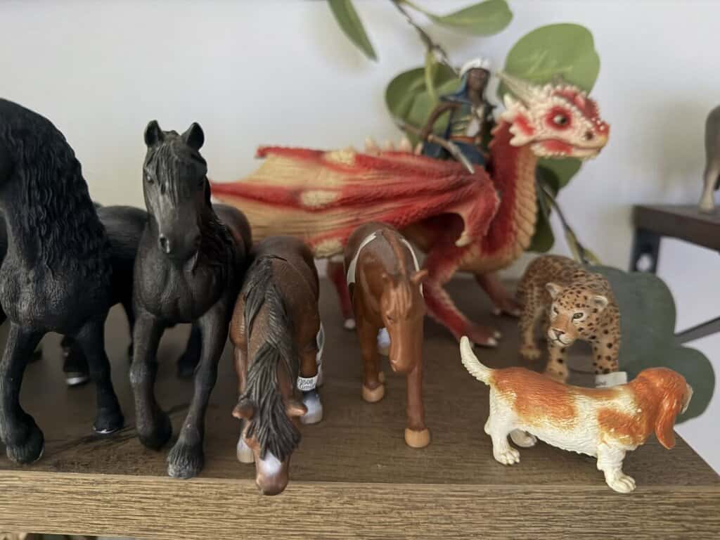 Figurky koní a draka na dřevěném povrchu, detailní modely hraček.