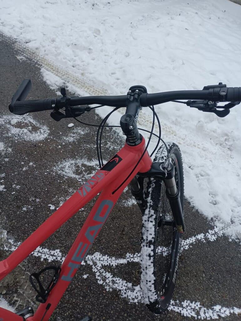 Horské kolo s červeným rámem na zimní cyklistiku.