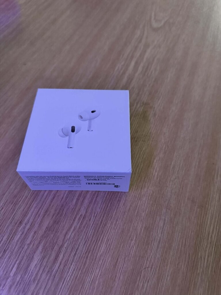 Bílá krabička s Apple AirPods Pro na dřevěném povrchu.