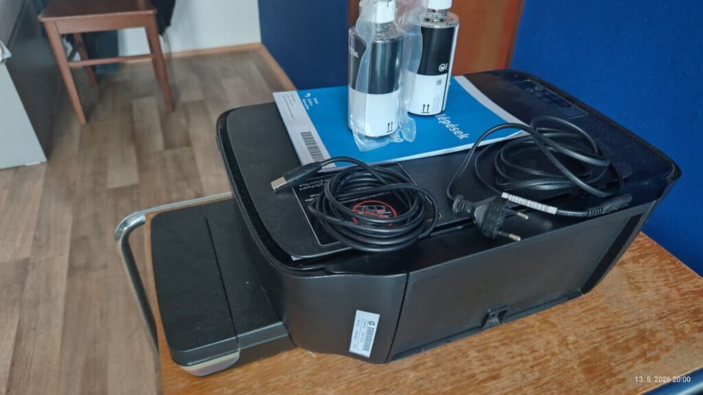 Tiskárna s kabely a náplněmi na stole, připravena k použití.