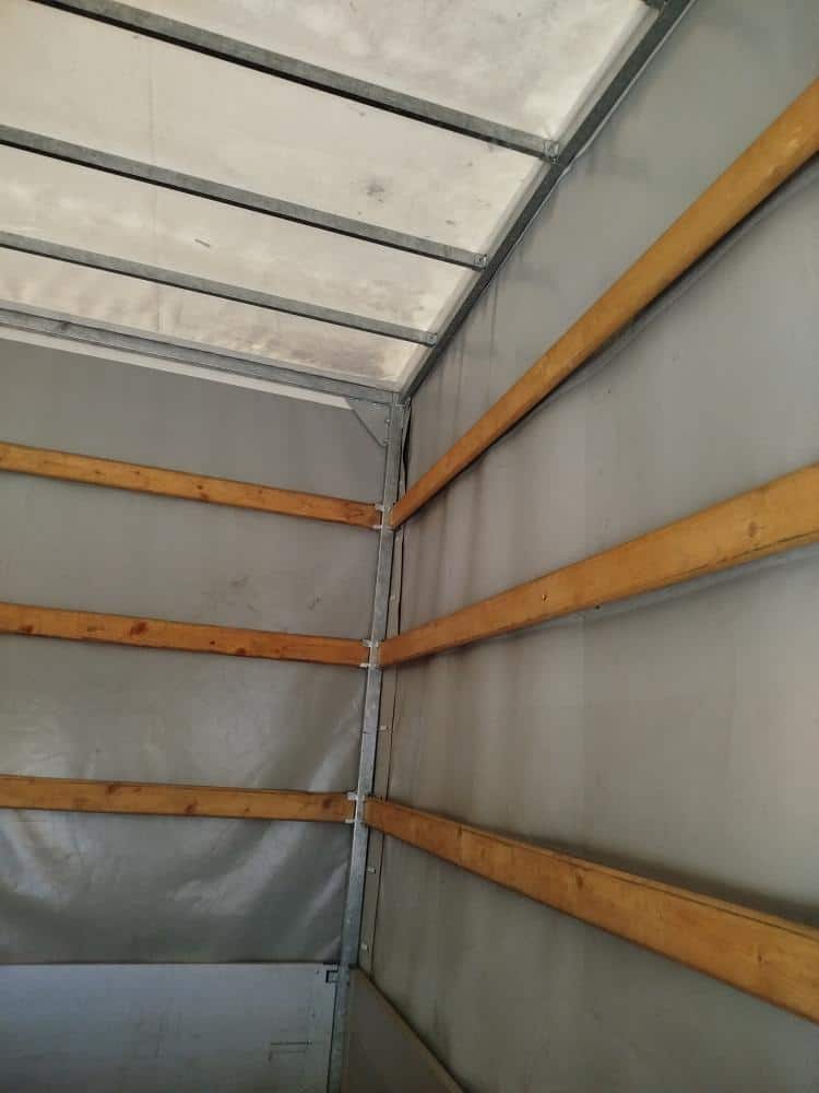 Interiér dodávky s dřevěnými lištami na stěnách.